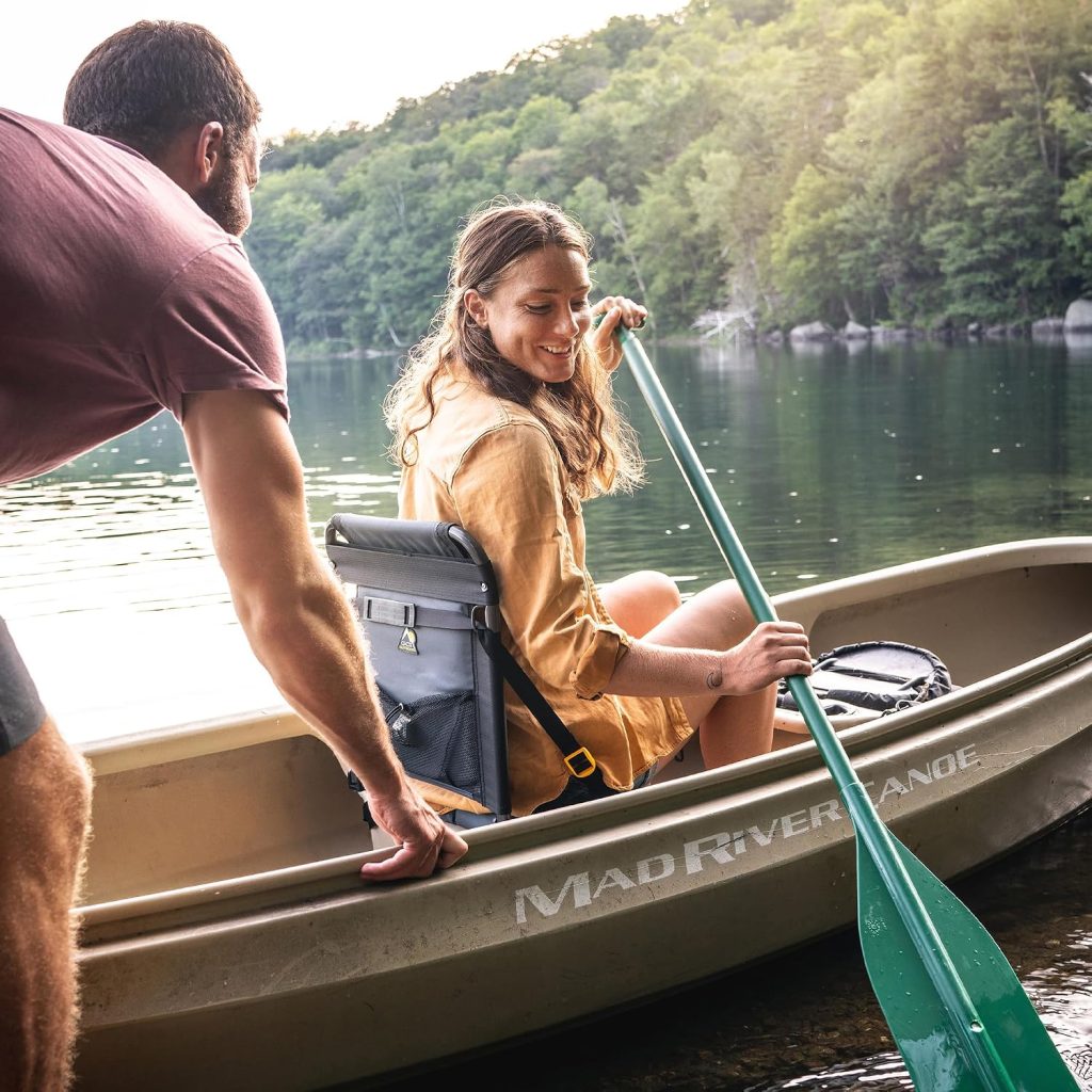 Paddler using the GCI Outdoor SitBacker canoe seat with back support in a canoe on a lake